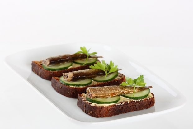 Sandwiches with sprats and cucumber on black bread