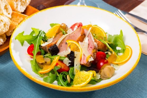 Festive salad with duck, arugula, orange and prunes 